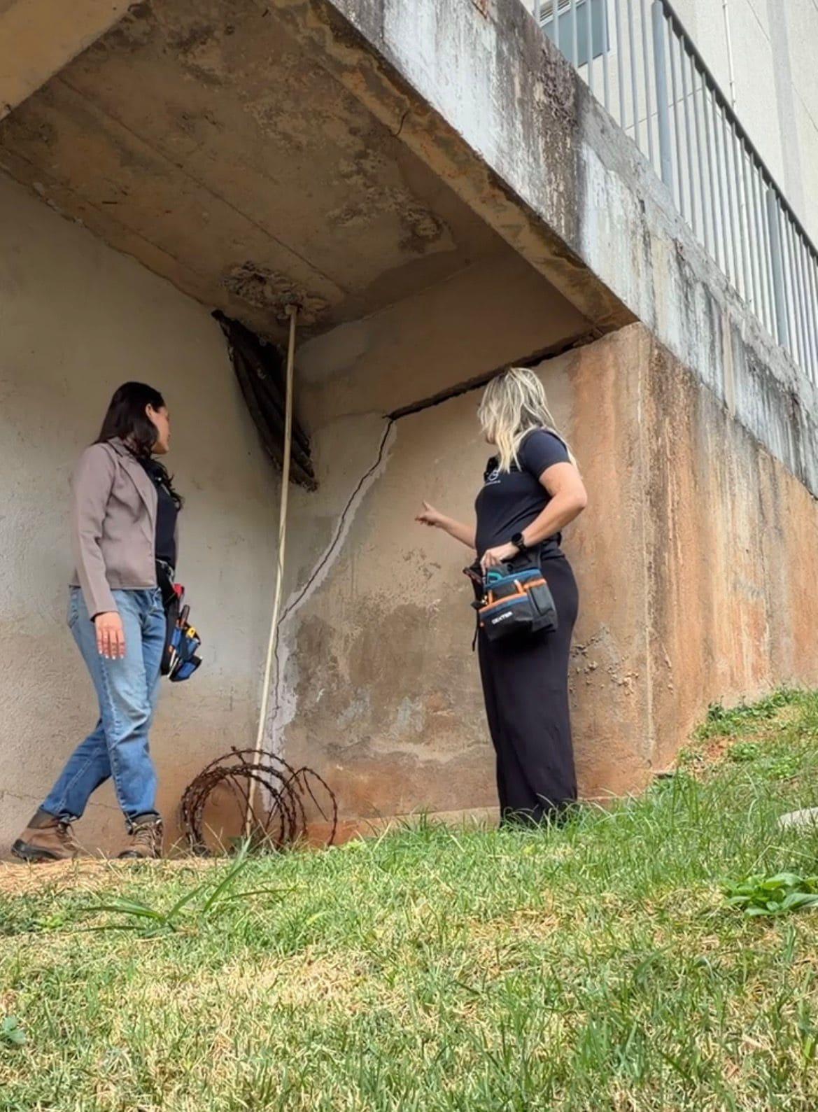 Engenheiras examinando uma fissura na fundação de um imóvel